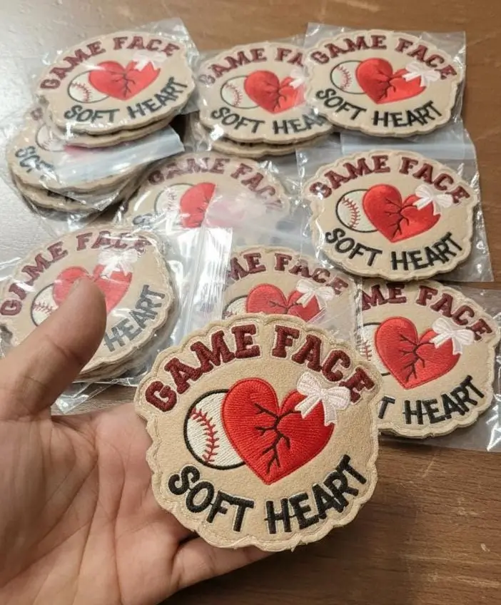 Hand holding Game Face Soft Heart custom embroidered patches showing tight weave and high detail