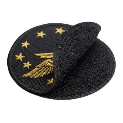 A black tactical embroidered patch being separated from its hook-and-loop velcro. backing, ideal for gear swaps.