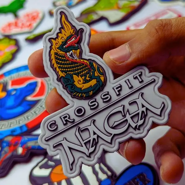 Close-up of a CrossFit Naga custom PVC patch held in a hand, showcasing sharp 3D lines and a detailed dragon emblem.