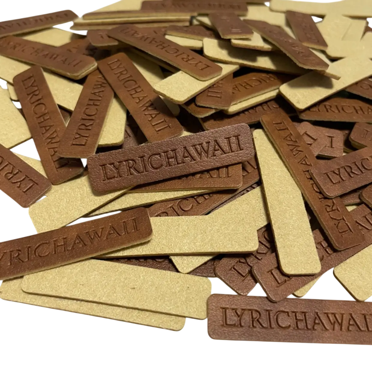 A bulk stack of rectangular genuine leather patches with deep heat-debossed branding, showing the natural grain and precision of a custom brass die stamp.