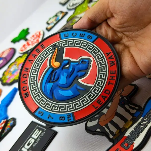 A large-scale tactical PVC patch featuring a blue bull and the phrase Molon Labe, held to show its durable rubber texture and depth.