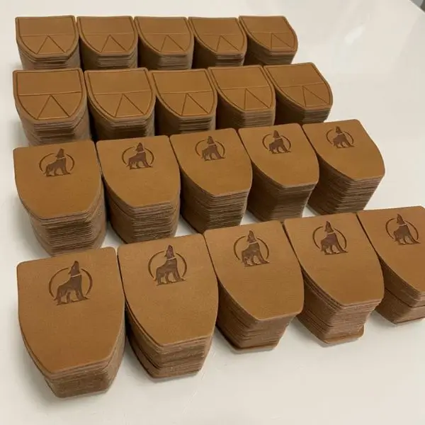 Tan shield-shaped leather patches with a debossed wolf silhouette for tactical branding.