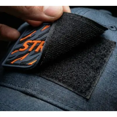 Close-up of a custom tactical PVC patch being removed to show the heavy-duty Velcro hook-and-loop backing on a cap.