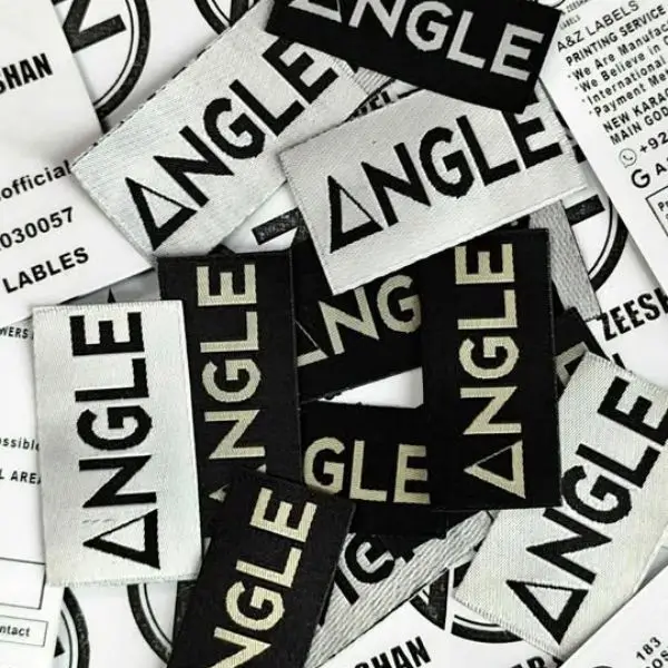 A pile of high-contrast custom woven clothing labels for a fashion brand, showing sharp, bold text branding.