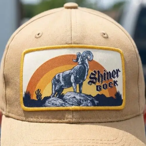 Detailed custom woven patch with a retro ram and landscape design on a tan baseball cap.