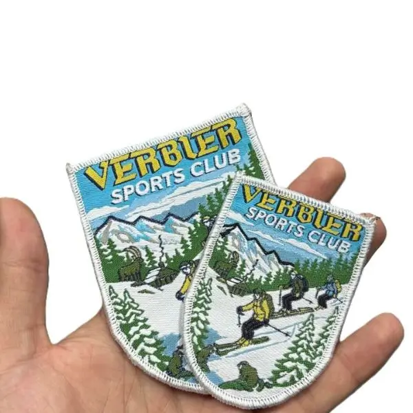 woven shield patches for a ski club, capturing complex scenic details and tiny skiers that standard embroidery cannot achieve.