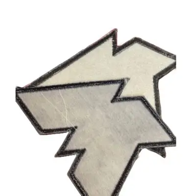 The back side of two custom-shaped jagged patches showing the stiff buckram and plastic sew-on backing used to provide professional structure and prevent fabric wrinkling.