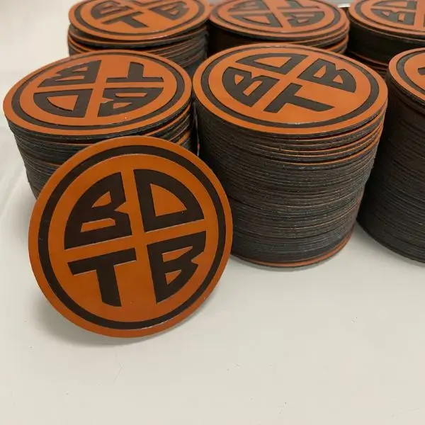 Stacks of circular tan leather patches featuring a black debossed BDTB logo.