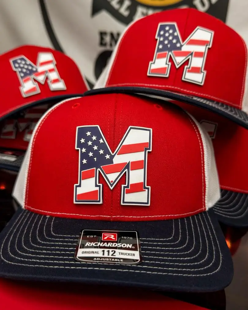 Red and navy Richardson trucker hats displaying custom 'M' shaped PVC patches with an American flag design.