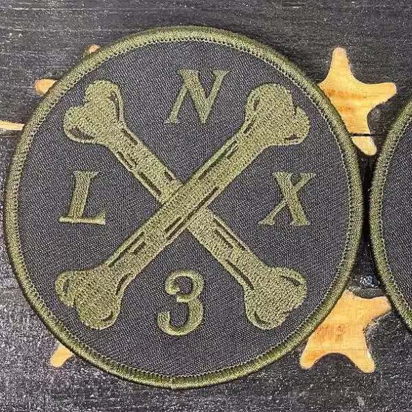 Custom tactical embroidered patch with dark background, olive green crossed bones, and NLX 3 text.