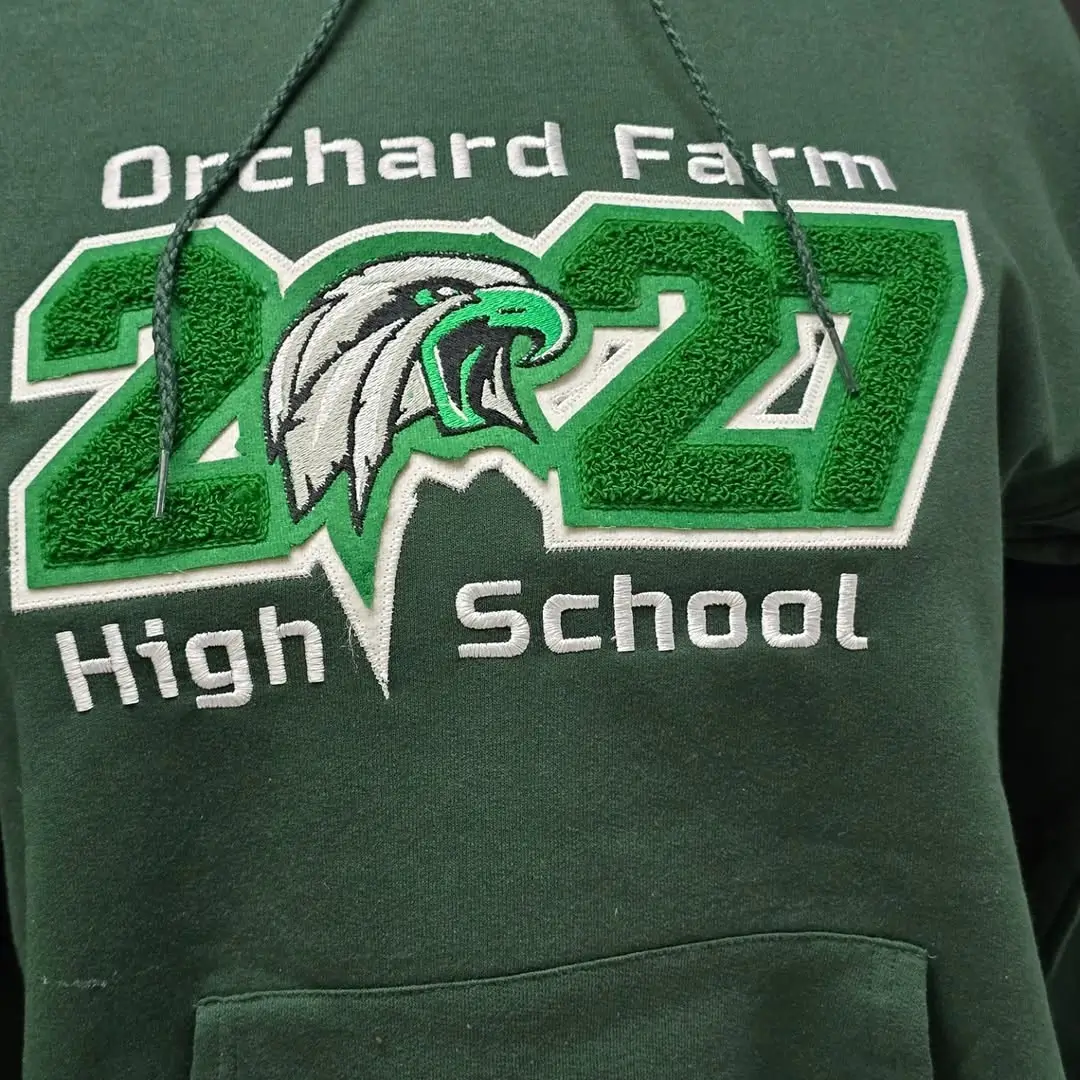 Green hoodie featuring custom chenille and embroidered Orchard Farm 2027 High School text with an eagle mascot.